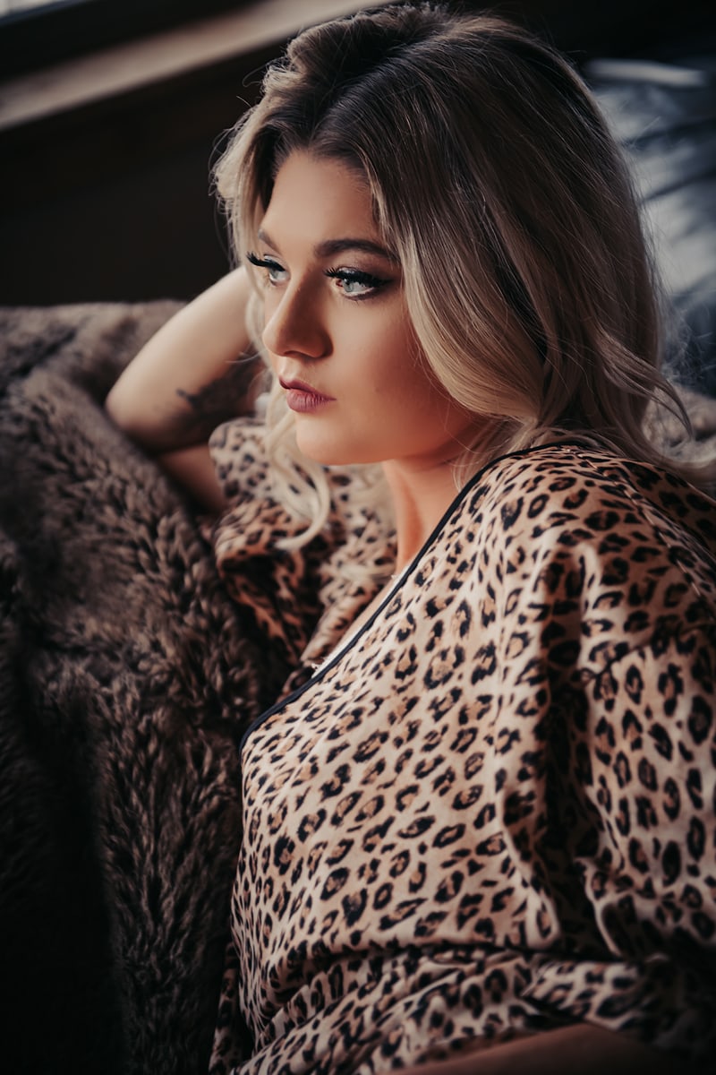 Boudoir Photography, woman in leopard print night gown sits on couch