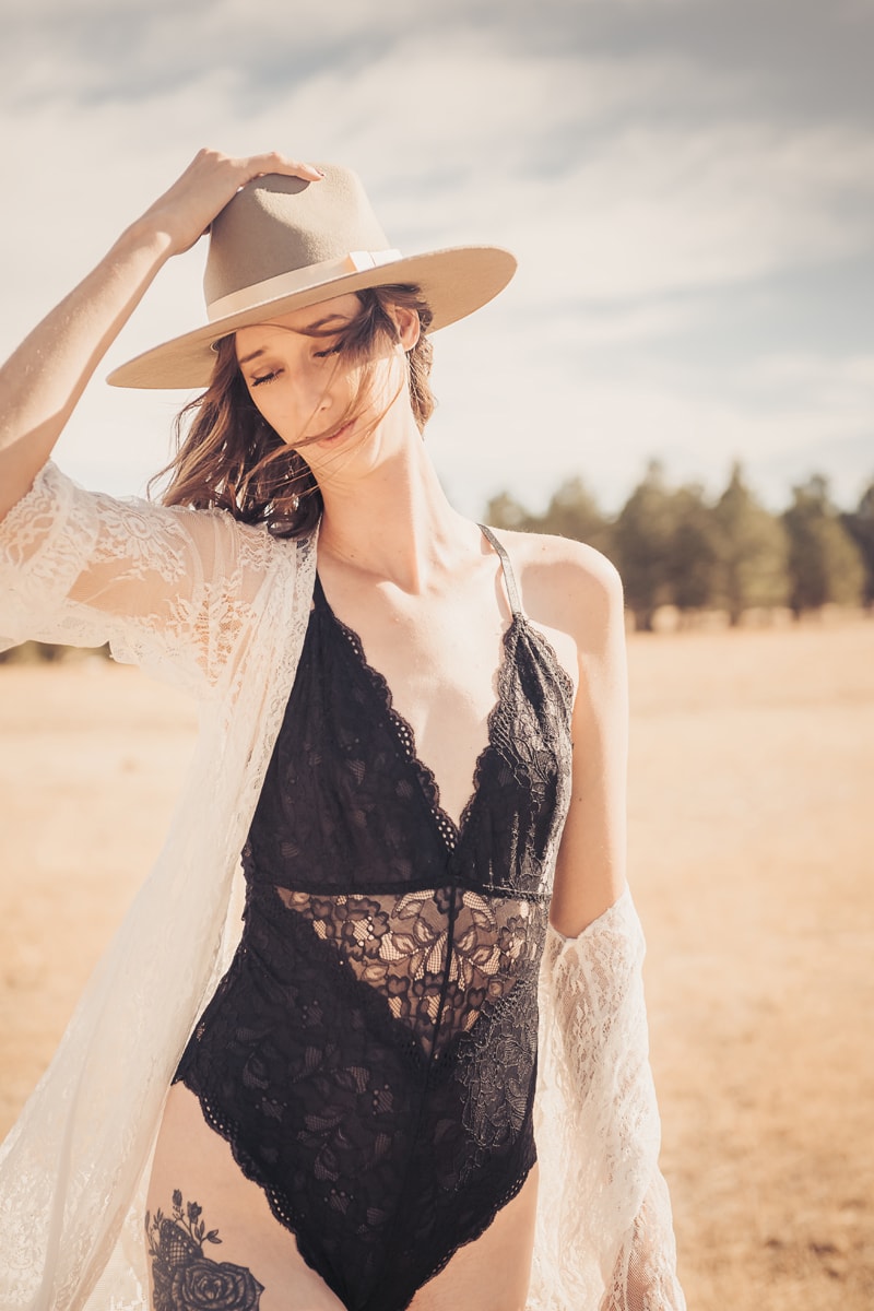 Boudoir Photography, woman in lingerie outdoors holds her hat in the wind